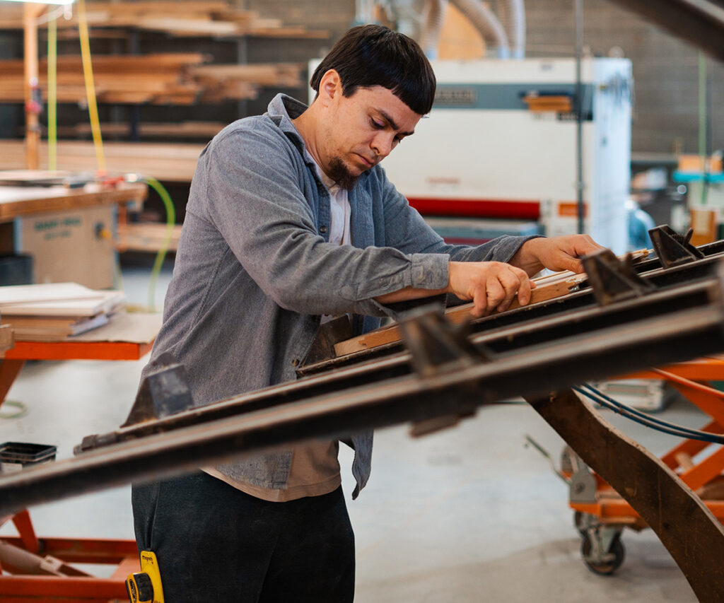 A man skillfully assembling a small piece of furniture in a well-equipped workshop, surrounded by tools and materials